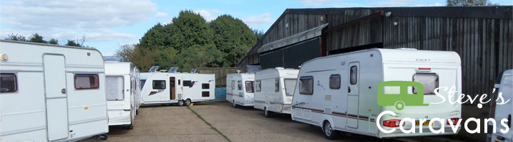 Touring caravans lined up in the yard in front of the barn, with the Steve’s Caravans logo